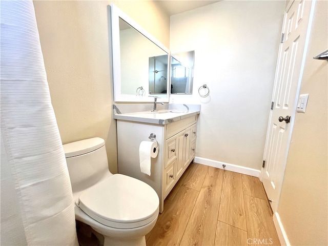 bathroom with vanity, wood finished floors, toilet, and baseboards