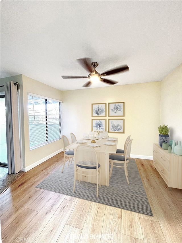 dining area with light wood-style floors, ceiling fan, baseboards, and a textured ceiling