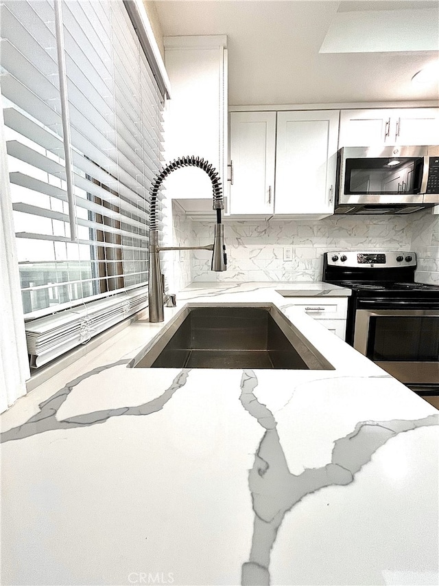 kitchen with white cabinetry, appliances with stainless steel finishes, decorative backsplash, and a sink