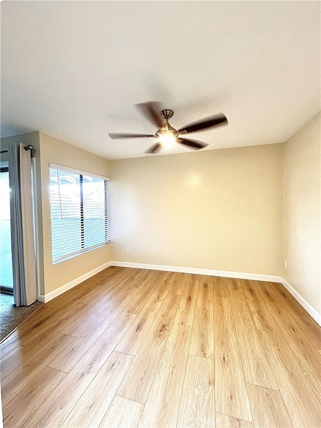 empty room featuring ceiling fan, baseboards, and wood finished floors