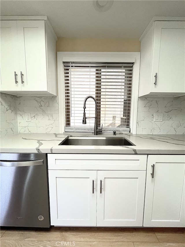 kitchen featuring light countertops, white cabinetry, a sink, and stainless steel dishwasher