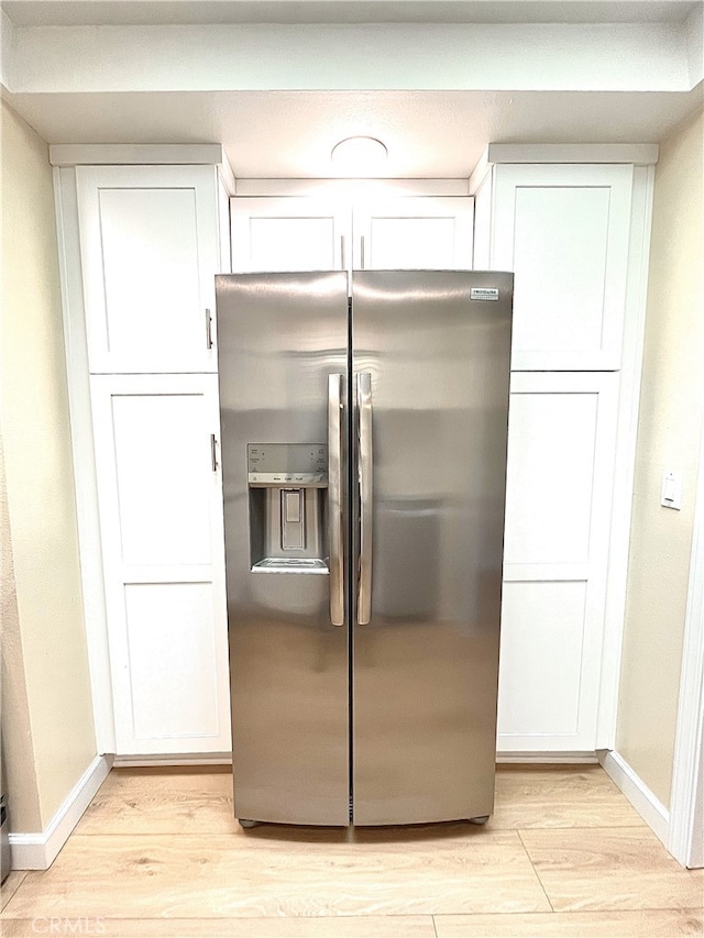 kitchen with white cabinetry, light wood-style flooring, baseboards, and stainless steel refrigerator with ice dispenser