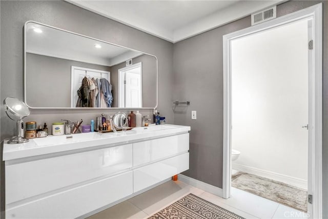 bathroom with toilet, vanity, and tile patterned floors