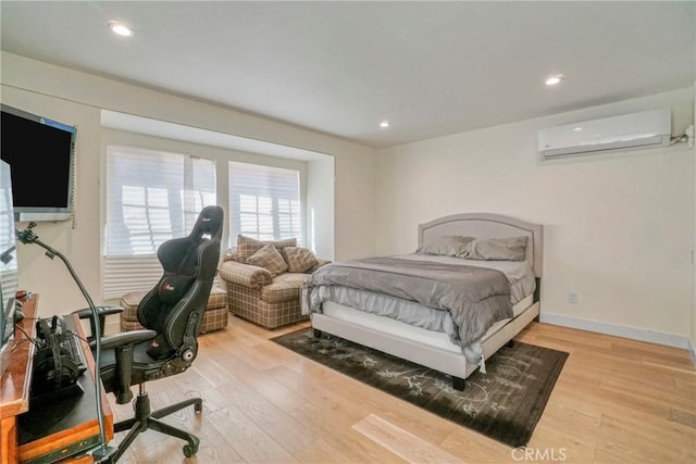 bedroom featuring light hardwood / wood-style flooring and an AC wall unit