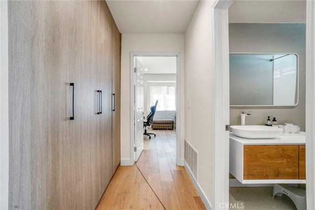 hallway with light hardwood / wood-style floors and sink