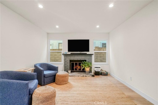 living room featuring light hardwood / wood-style flooring and a brick fireplace