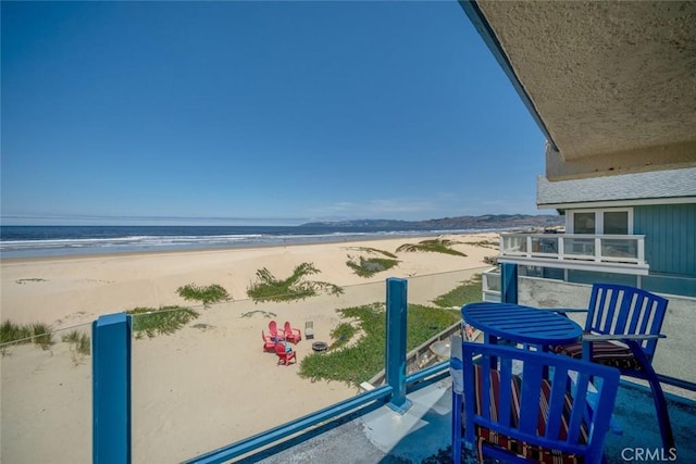 balcony with a water view and a view of the beach