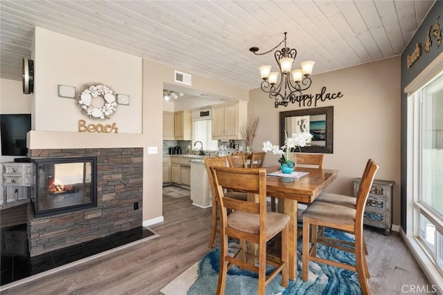 dining space with a fireplace, wood-type flooring, an inviting chandelier, and wood ceiling