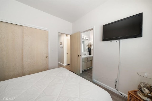 bedroom featuring wood-type flooring, connected bathroom, a closet, and sink