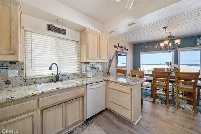 kitchen with kitchen peninsula, dishwasher, light hardwood / wood-style floors, and sink