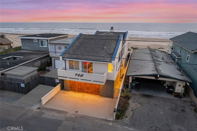 aerial view at dusk featuring a beach view and a water view