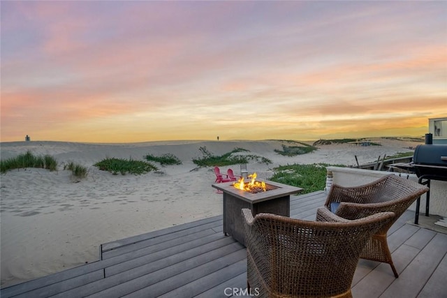 deck at dusk with a water view and an outdoor fire pit