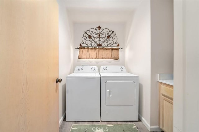 washroom with cabinets, washer and clothes dryer, and wood-type flooring