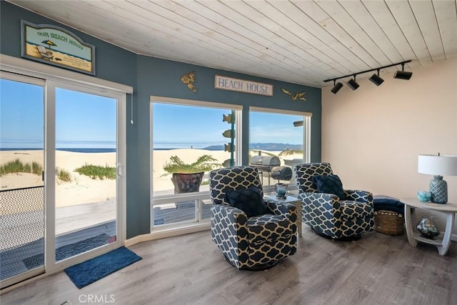 living area with a water view, track lighting, hardwood / wood-style flooring, and wood ceiling