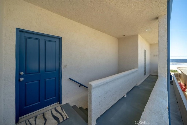 view of exterior entry featuring a balcony and a water view