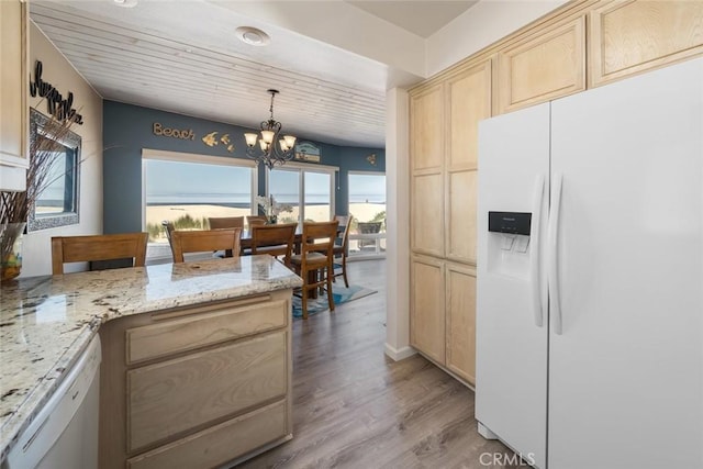 kitchen with light stone countertops, light hardwood / wood-style flooring, a notable chandelier, decorative light fixtures, and white appliances