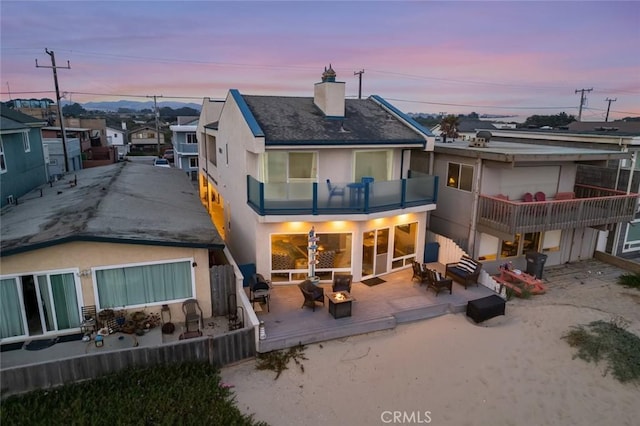 back house at dusk with a balcony and a deck