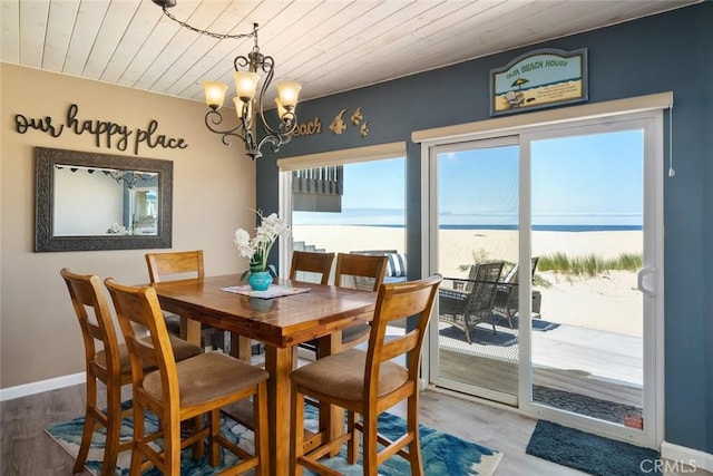 dining room with a chandelier, a water view, hardwood / wood-style flooring, and wood ceiling