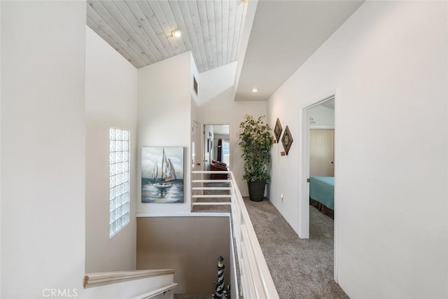 hall featuring carpet, wooden ceiling, and lofted ceiling