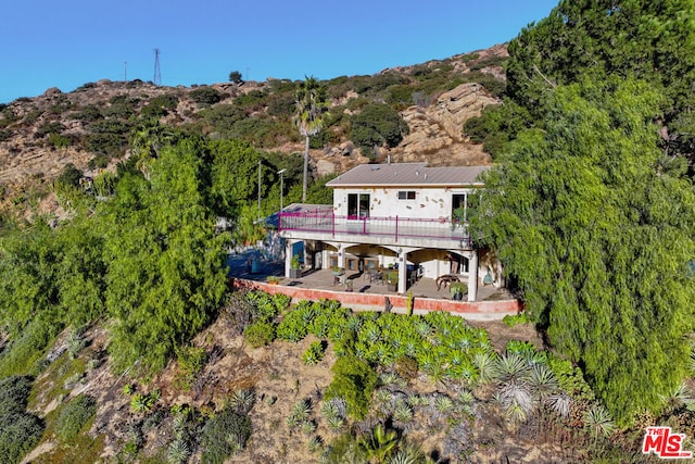 rear view of house featuring a deck with mountain view and a patio