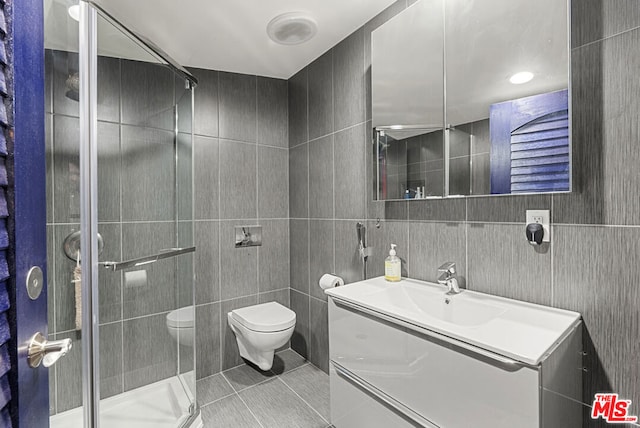 bathroom featuring tile patterned flooring, vanity, tile walls, and toilet