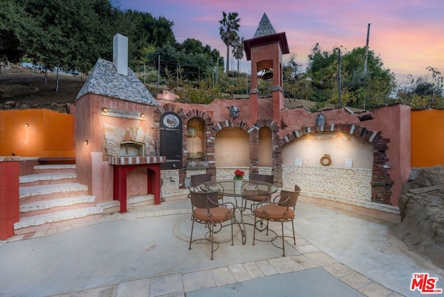 patio terrace at dusk with an outdoor fireplace