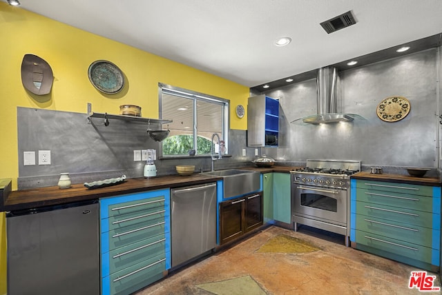 kitchen with appliances with stainless steel finishes, backsplash, wall chimney range hood, sink, and butcher block counters