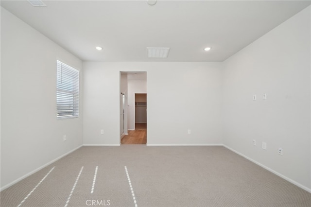 unfurnished bedroom featuring a walk in closet and light colored carpet