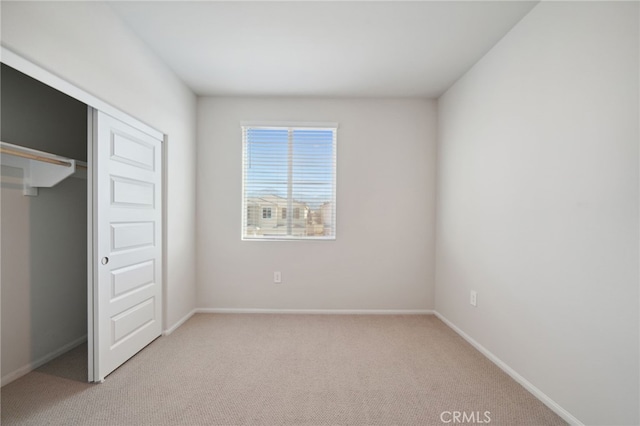 unfurnished bedroom with light carpet and a closet