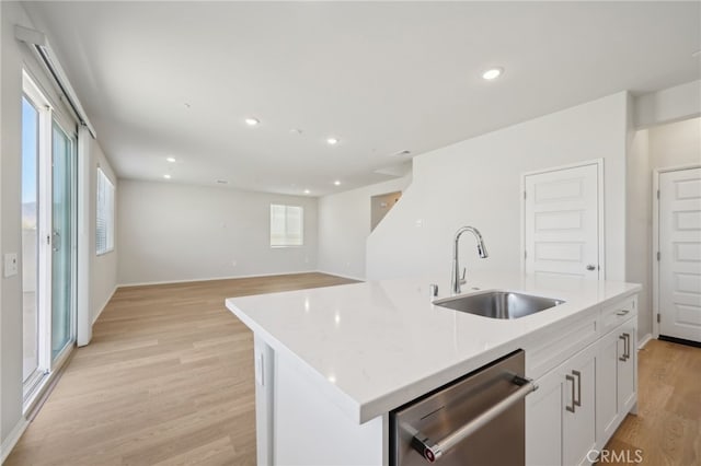 kitchen with sink, light wood-type flooring, stainless steel dishwasher, a kitchen island with sink, and white cabinets