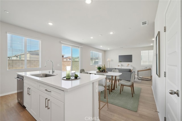 kitchen featuring white cabinetry, an island with sink, light hardwood / wood-style floors, and sink