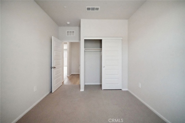 unfurnished bedroom with light carpet and a closet