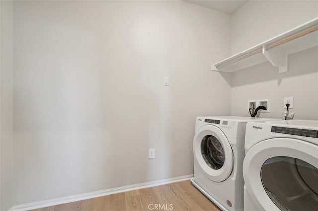 clothes washing area featuring washing machine and dryer and light hardwood / wood-style flooring