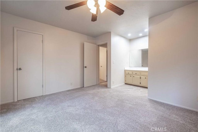 unfurnished bedroom featuring ensuite bath, ceiling fan, and light colored carpet