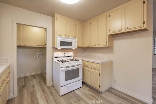 kitchen with white appliances, cream cabinets, and light hardwood / wood-style flooring