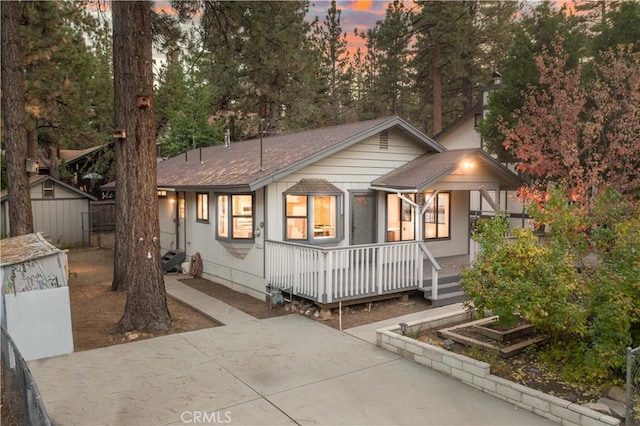 2028 Manzanita Ln, Big Bear City, CA 92314 - view of front facade with a porch, a shingled roof, and a shed