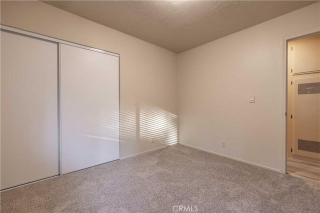 unfurnished bedroom featuring light carpet, a textured ceiling, and a closet