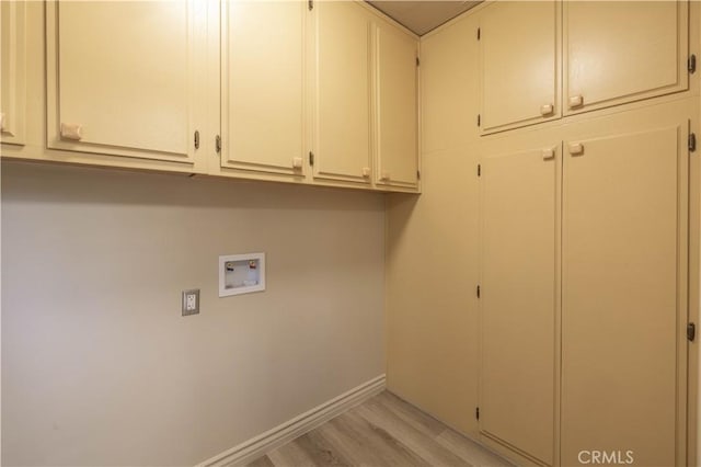 laundry room with washer hookup, light hardwood / wood-style floors, and cabinets