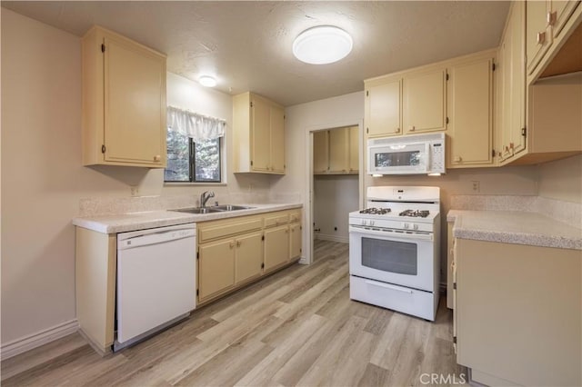 kitchen featuring cream cabinetry, light hardwood / wood-style floors, white appliances, and sink