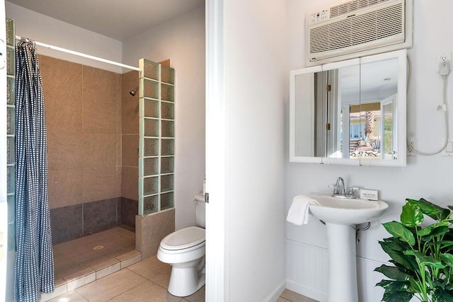 bathroom with tile patterned floors, a shower with curtain, toilet, and a wall unit AC