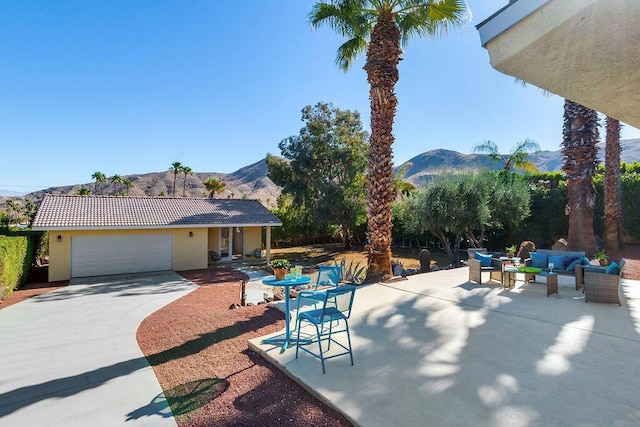 view of patio with a mountain view, an outdoor living space, and a garage