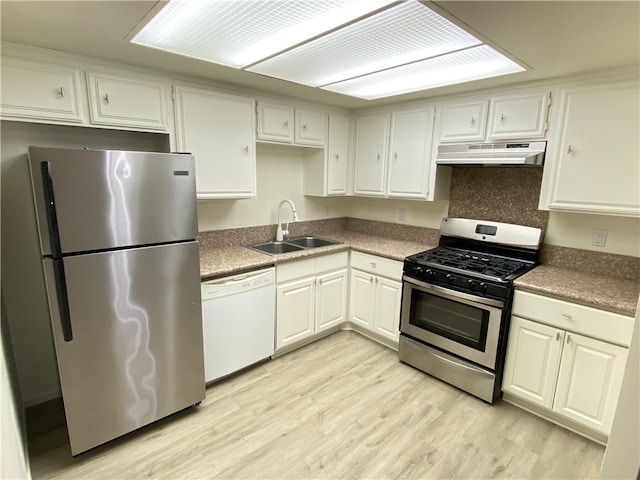 kitchen featuring light wood-style flooring, appliances with stainless steel finishes, white cabinets, a sink, and under cabinet range hood