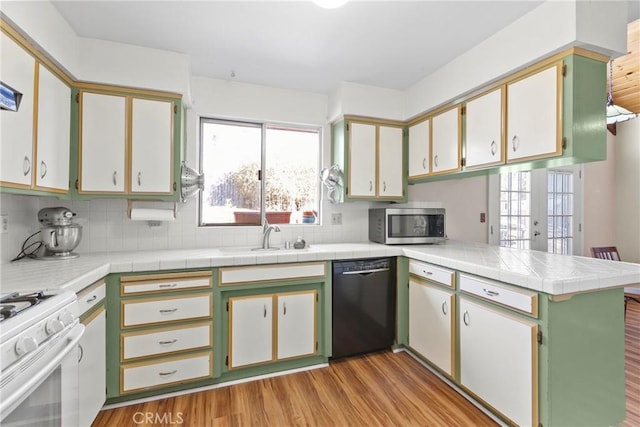 kitchen with black dishwasher, backsplash, kitchen peninsula, light hardwood / wood-style floors, and white stove