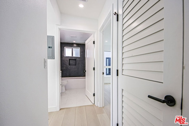 corridor with electric panel and light wood-type flooring