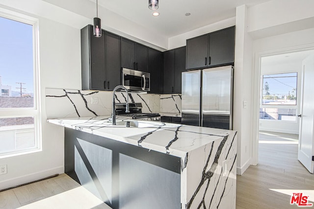 kitchen with light wood-type flooring, kitchen peninsula, stainless steel appliances, and hanging light fixtures