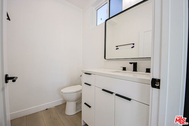 bathroom featuring hardwood / wood-style flooring, vanity, and toilet