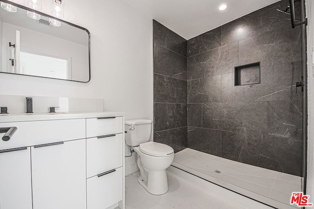 bathroom with tiled shower, vanity, and toilet