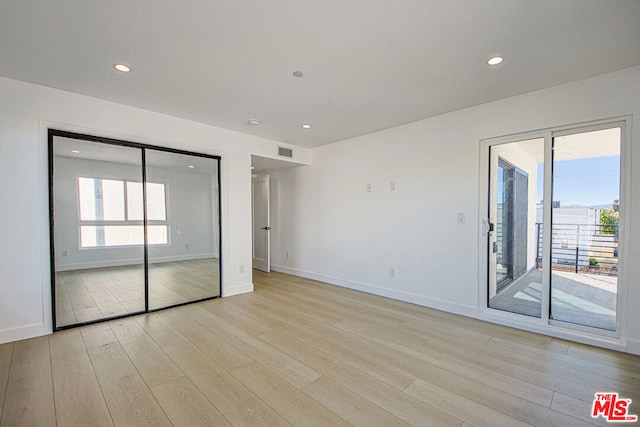 unfurnished bedroom with access to outside, light hardwood / wood-style flooring, and multiple windows