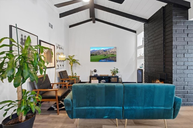 living room featuring a fireplace, beam ceiling, hardwood / wood-style flooring, and high vaulted ceiling