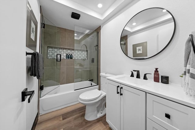 full bathroom featuring toilet, hardwood / wood-style floors, vanity, and combined bath / shower with glass door